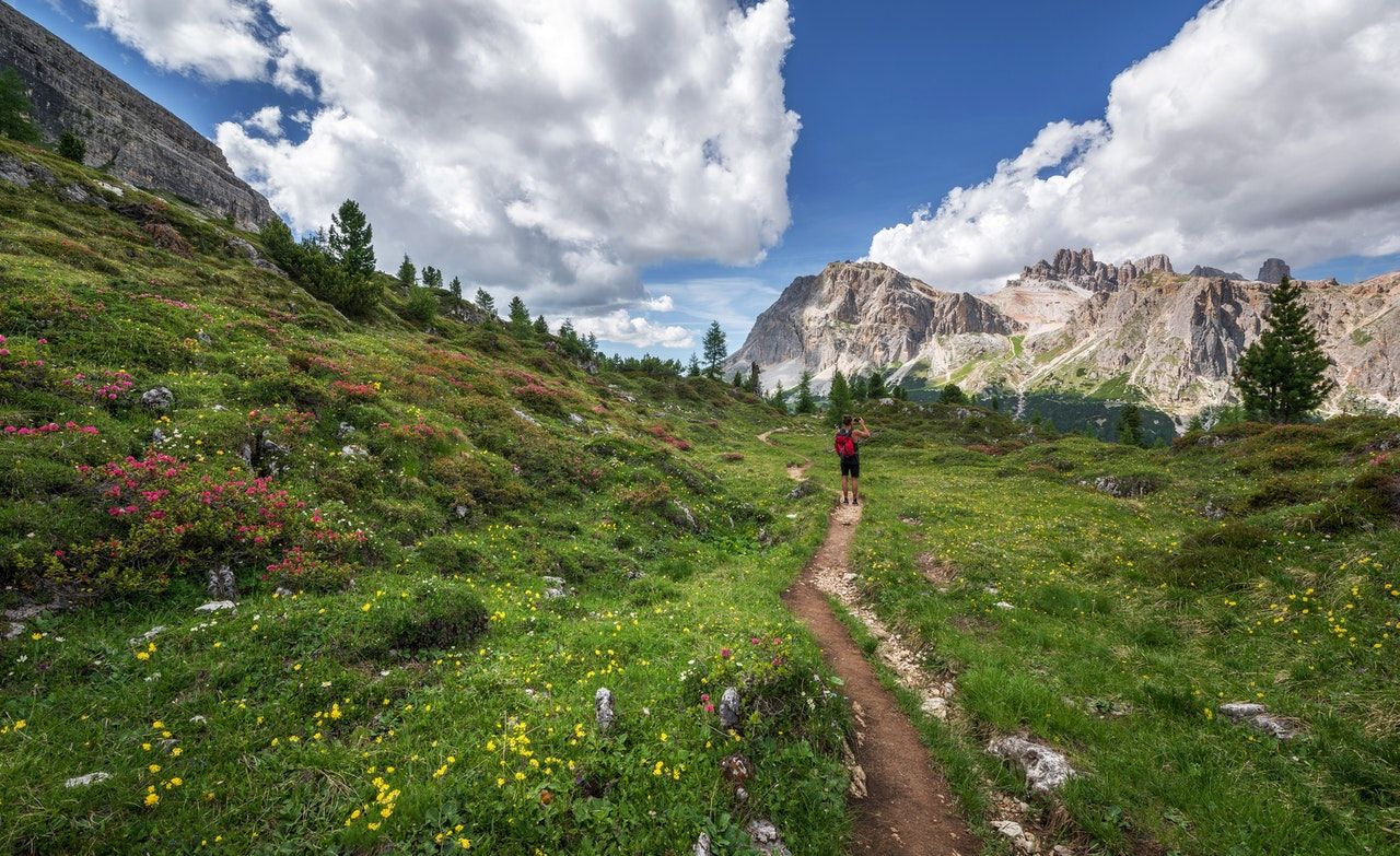 Runner on a trail in the mountains, stopping to take a picture of the view.