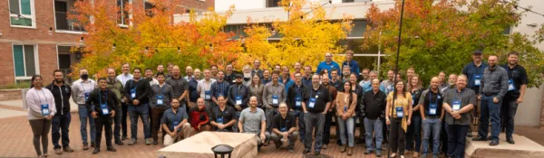 GDevCon N.A. conference attendees standing in front of several trees showing fall colors - orange and yellow.