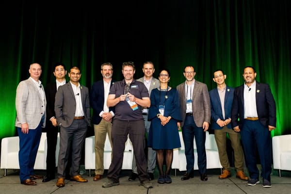 A picture of someone receiving an award. A person holding an award surrounded by various people in business suits.